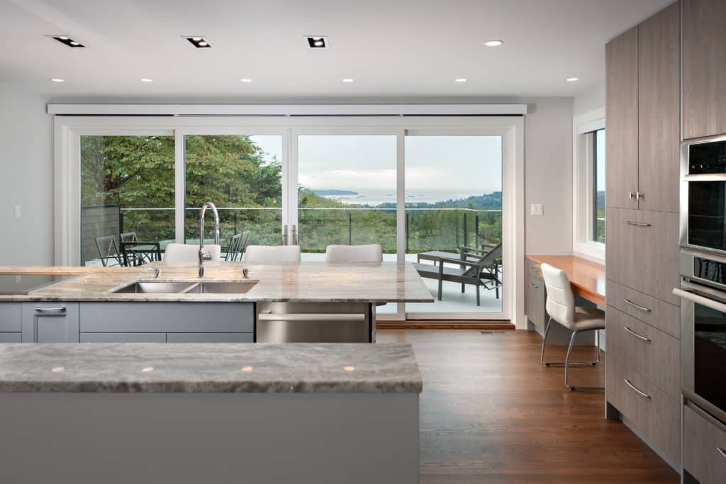 Balmoral kitchen after renovation, marble counters and a window wall opening to the deck and the water.