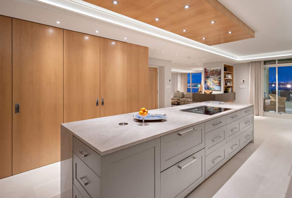 Sailor Retreat after renovation, a pale island and full-height wood cabinets under a panelled ceiling.