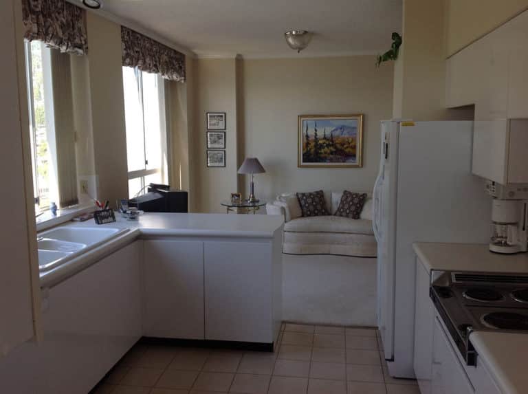 Sailor Retreat before renovation, white cabinets and a window seat under patterned valances.