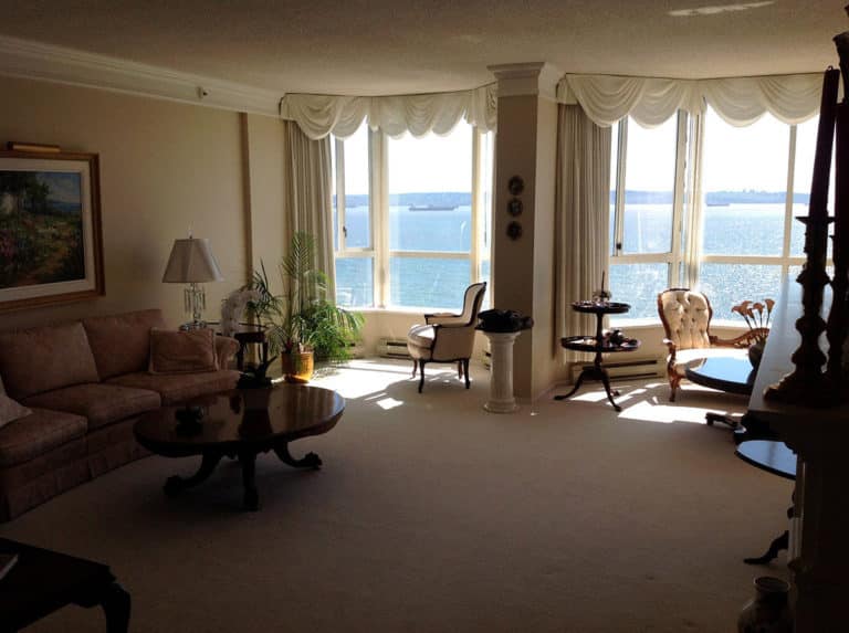 Sailor Retreat before renovation, swagged curtains and beige carpet in a room facing the water.