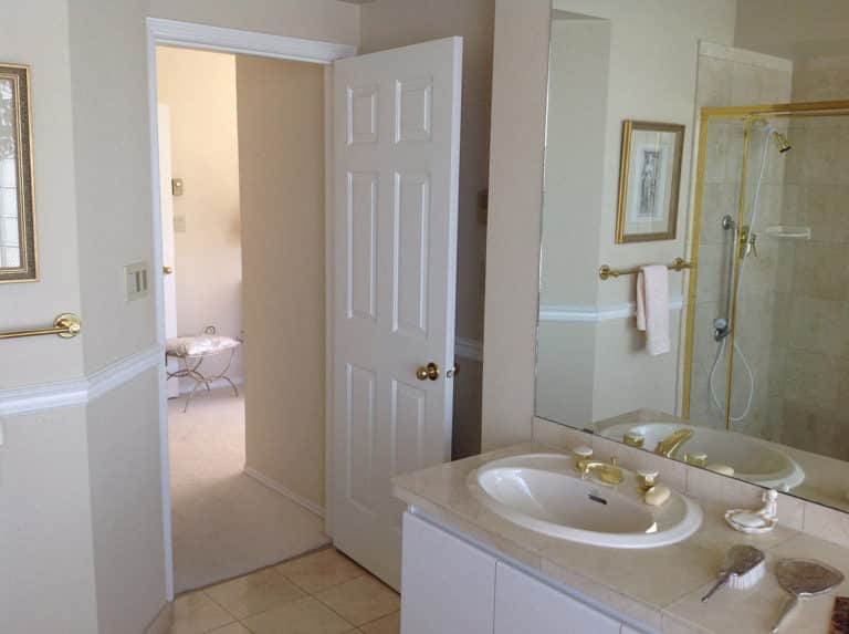 Sailor Retreat before renovation, a cream tiled bathroom with a drop-in tub and gold fittings.