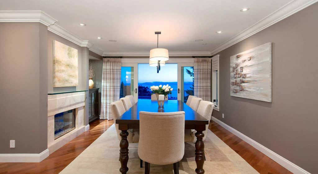 View Point before renovation, an oval dining table and linear fireplace in a taupe panelled room.
