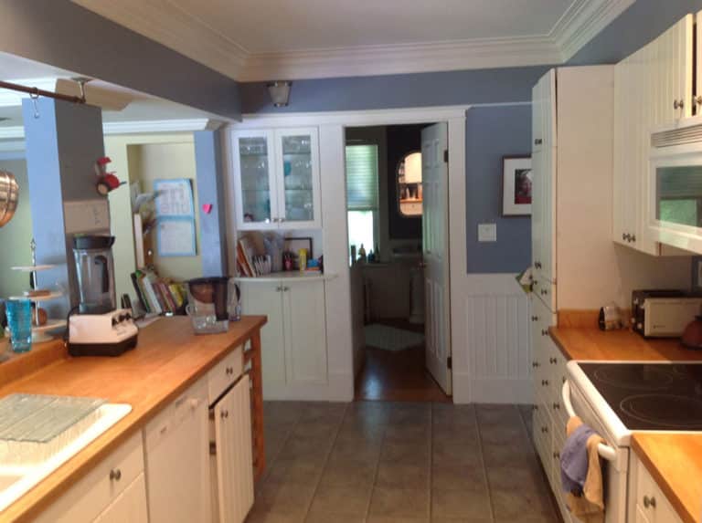 Queens before renovation, cream cabinets and wood counters against blue painted walls.