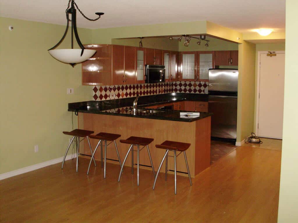 City Splendor before renovation, a black granite bar and dark cabinets under a glass pendant.
