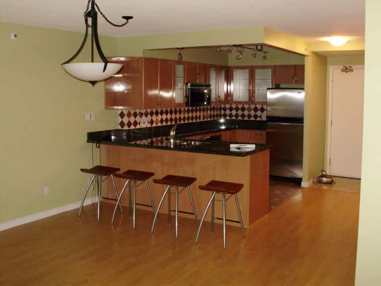 City Splendor before renovation, a black granite bar and dark cabinets under a glass pendant.