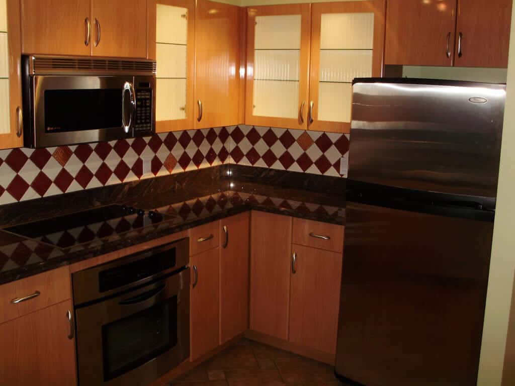 City Splendor before renovation, honey oak cabinets and a diamond tile backsplash above dark counters.