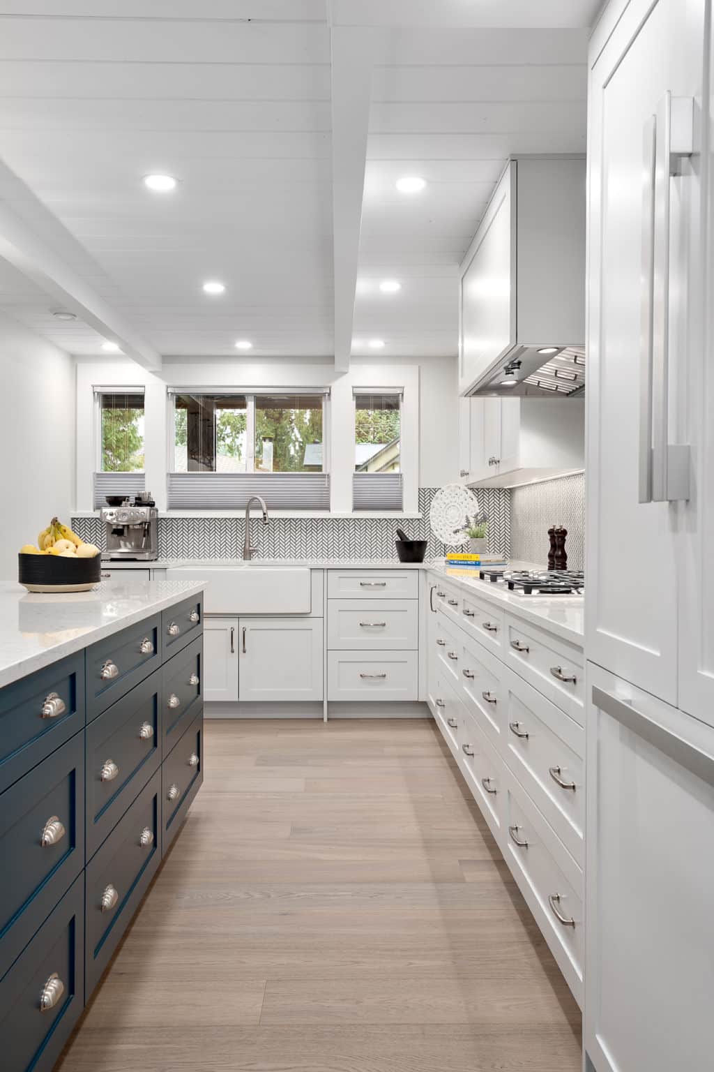 White kitchen with a navy island and a window over the sink