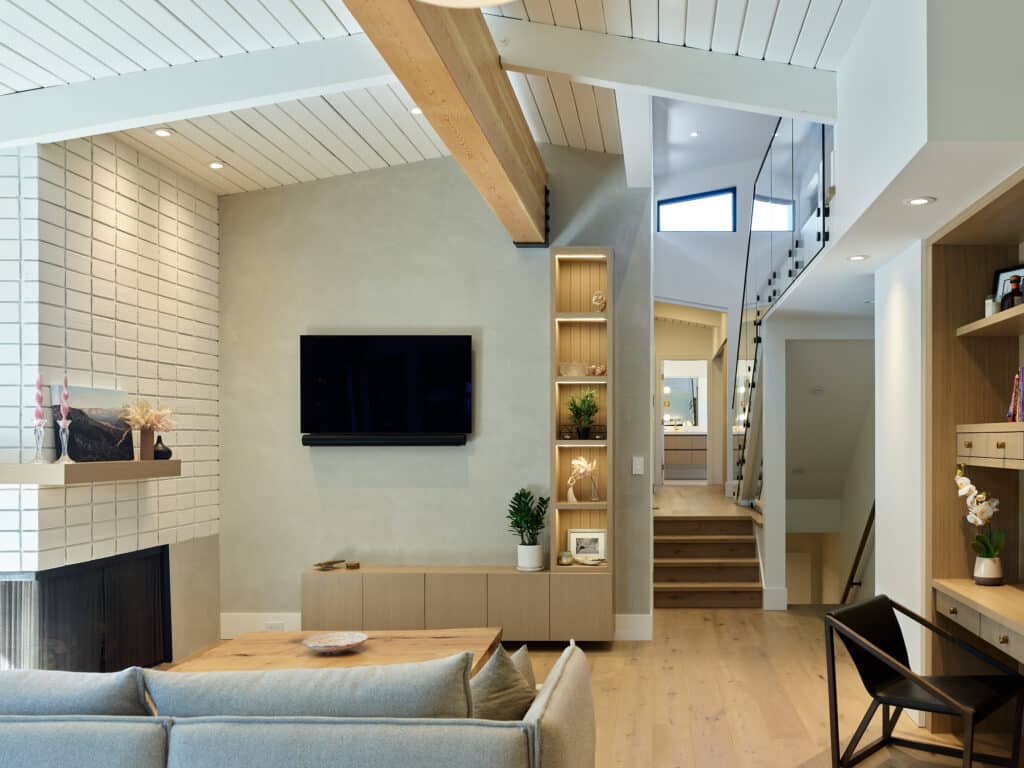 View Point living room with a white brick fireplace wall, vaulted plank ceiling and a pale sectional., after