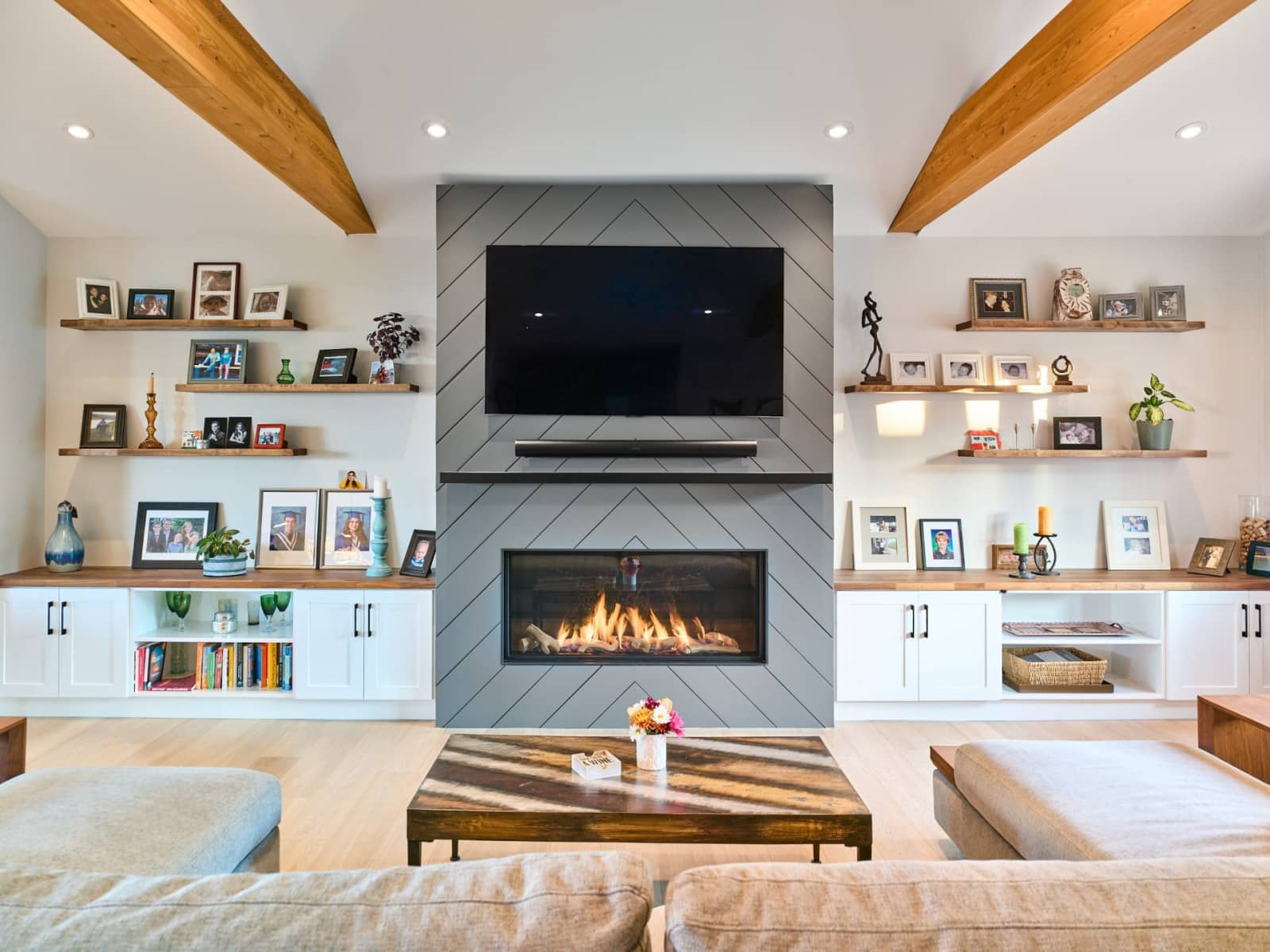 Living room of a custom home with exposed timber ceiling beams, linear gas fireplace and built-in millwork