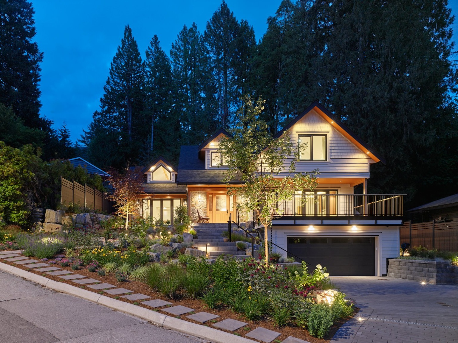 Custom home front elevation at dusk, stone base and timber entry