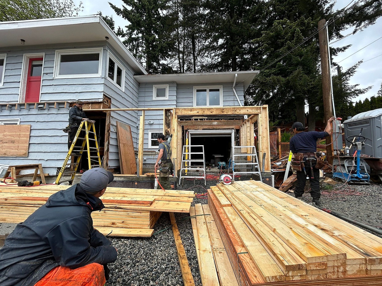 The crew framing the new front of the house, with lumber laid out on the driveway