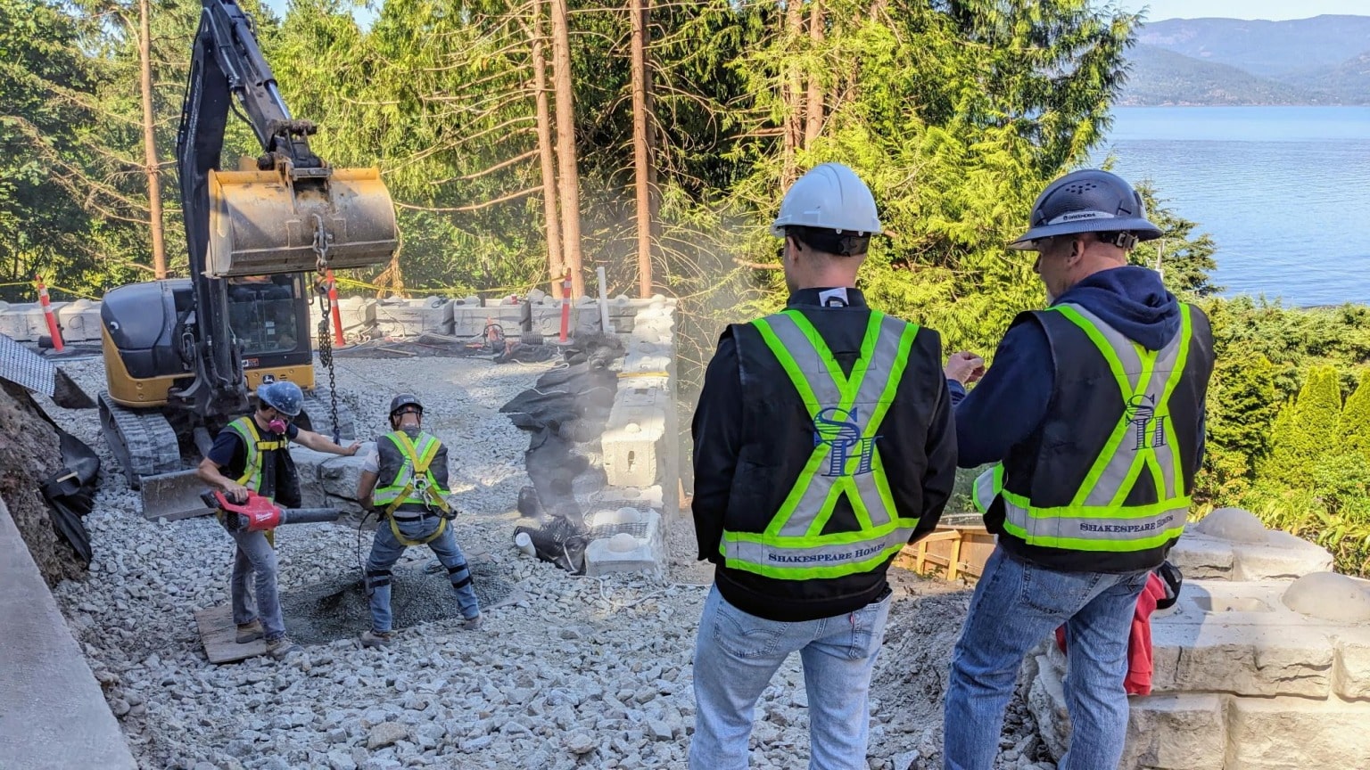 Two Shakespeare Homes supervisors watching the crew set retaining wall blocks above the water