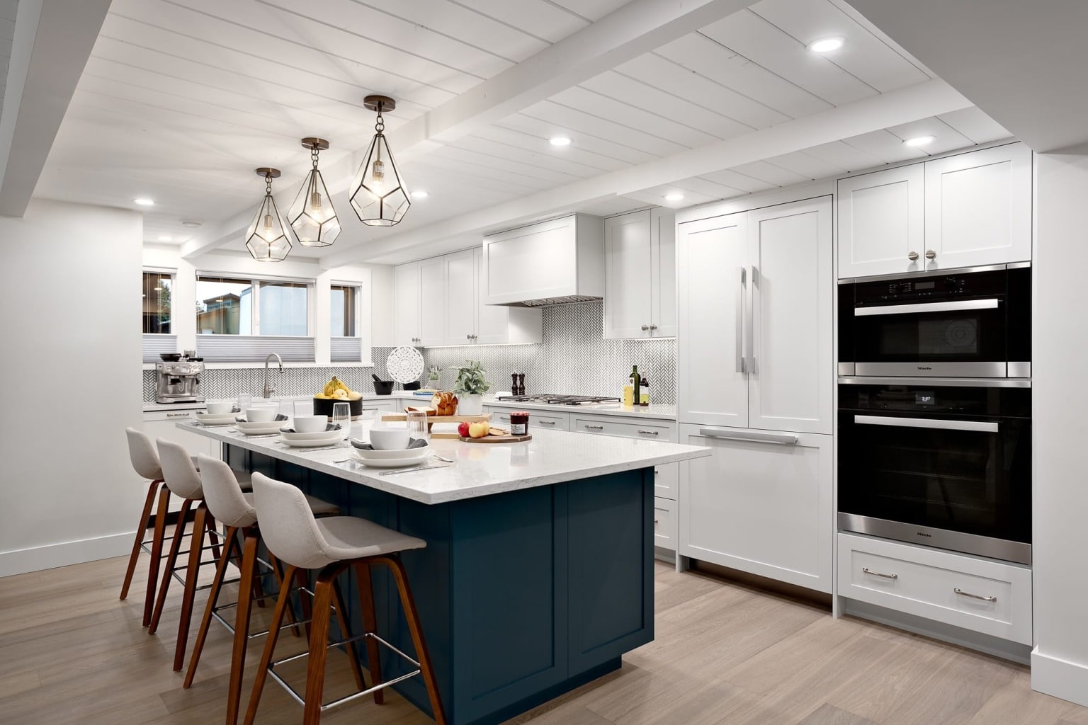Canyon kitchen with white cabinets, a deep navy island in quartz and stainless double wall ovens.